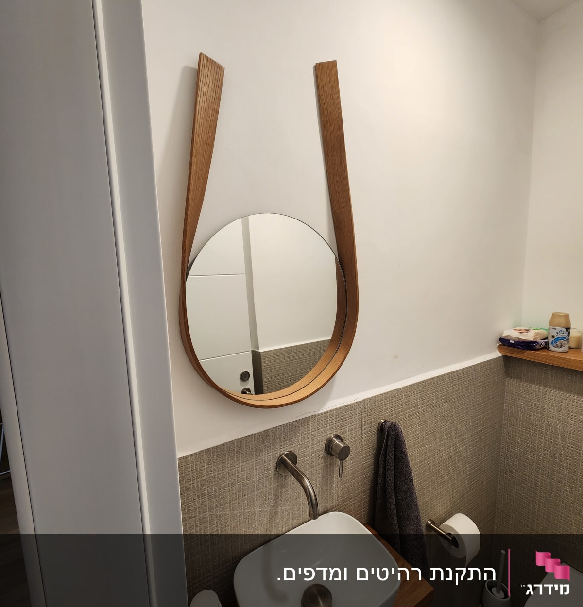 כיור עם ברז ומראה עגולה בחדר אמבטיה